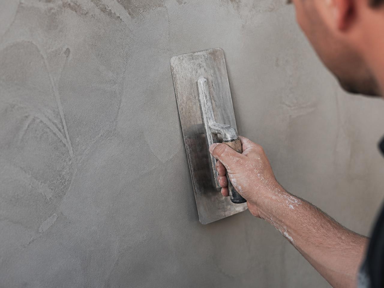 Hantverkare applicerar microcement med stålspackel på vägg